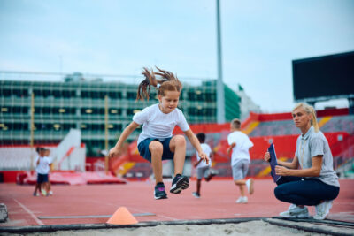 Little,Girl,Exercising,Long,Jump,During,Sports,Training,With,Her